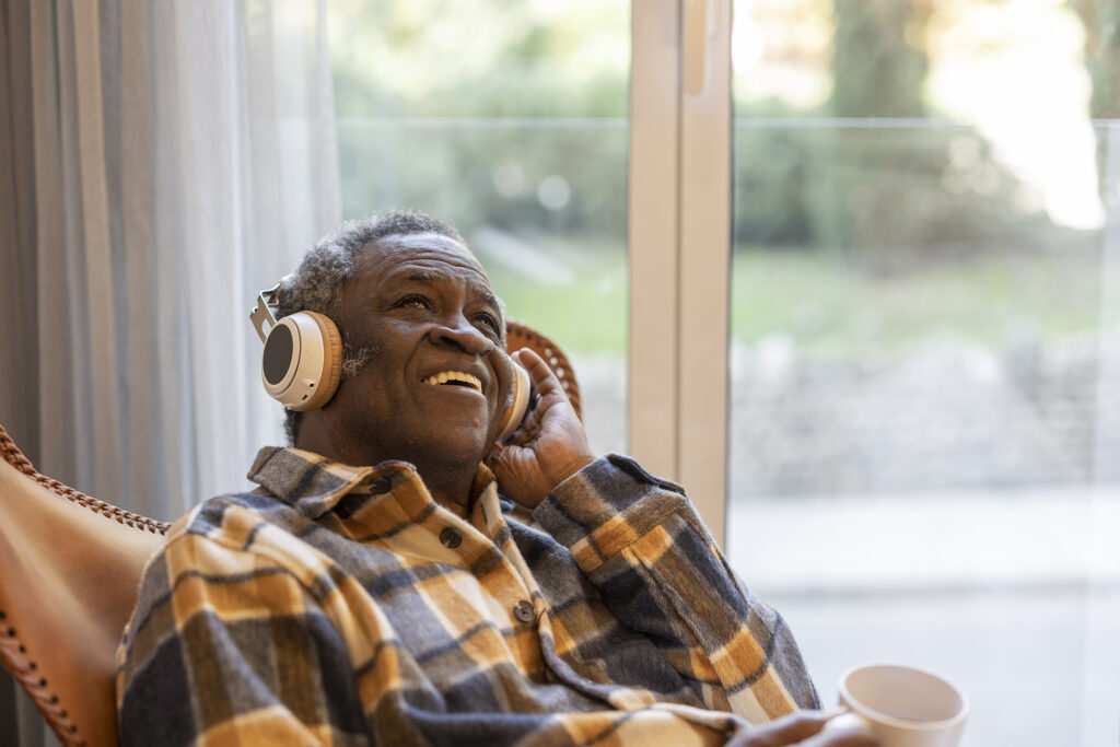 elderly pensioner at home listening to music with headphones